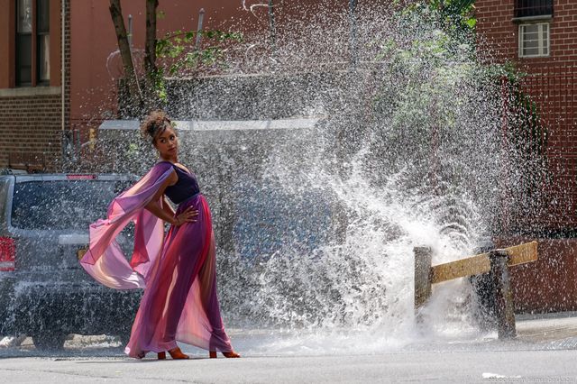 A photo of a woman posing while being sprayed by a fire hydrant